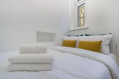 a white bed with yellow pillows and a window at Park Strzelecki Two-Level Apartment by BookingHost in Kraków