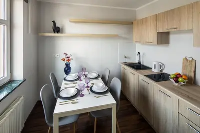 a kitchen with a white table with chairs and a tableasteryasteryasteryasteryastery at Corner House Residence in Kraków