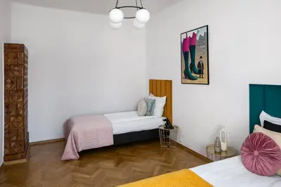 two beds in a room with white walls and wooden floors at Corner House Residence in Kraków