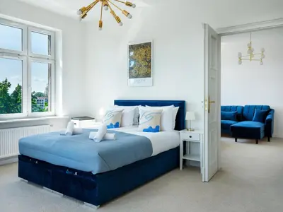 a bedroom with a blue bed and a blue chair at Castle View Apartments by Tyzenhauz in Kraków