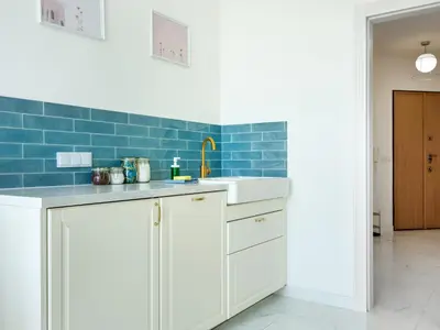 a kitchen with white cabinets and blue tiles at Castle View Apartments by Tyzenhauz in Kraków