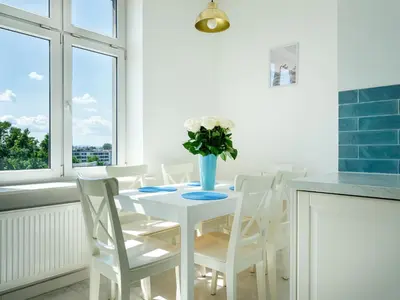 a white dining room table with white chairs and a vase with flowers at Castle View Apartments by Tyzenhauz in Kraków