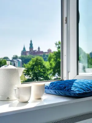 a window sill with three white cups and a blue blanket at Castle View Apartments by Tyzenhauz in Kraków