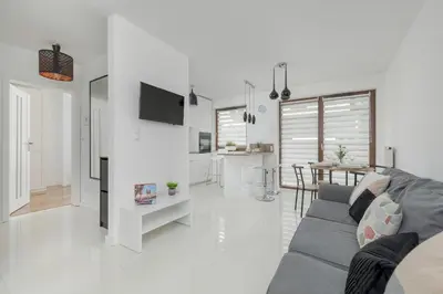 a white living room with a couch and a kitchen at Apartment with Garden in Kraków by Noclegi Renters in Kraków
