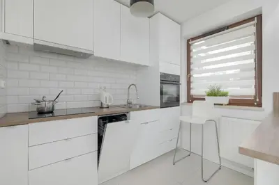 a white kitchen with white cabinets and a window at Apartment with Garden in Kraków by Noclegi Renters in Kraków
