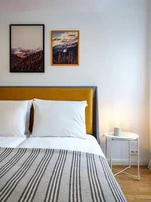 a bedroom with a bed with two pictures on the wall at Modern Central Apartment w. parking by Tyzenhauz in Kraków
