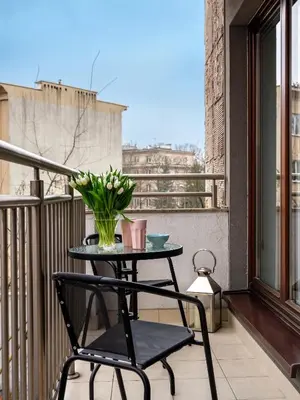 a table and a chair on a balcony with a vase of flowers at Modern Central Apartment w. parking by Tyzenhauz in Kraków