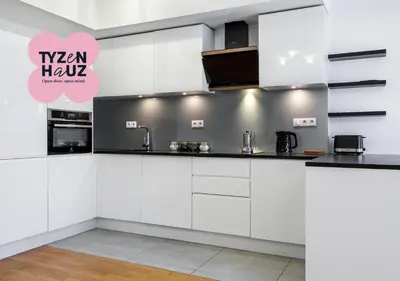 a kitchen with white cabinets and black counter tops at Modern Central Apartment w. parking by Tyzenhauz in Kraków