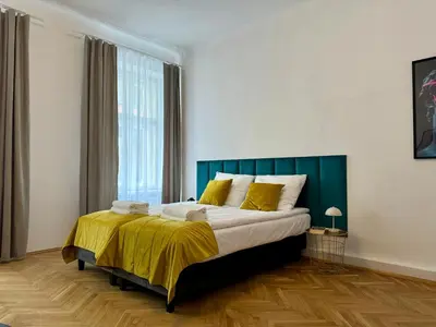 a bedroom with a large bed with yellow sheets at Millenium Apartments in Kraków