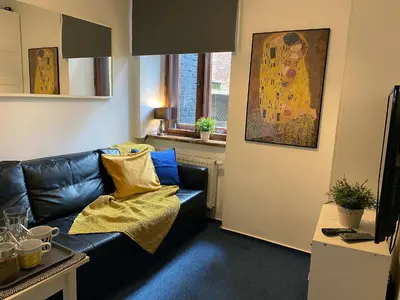a living room with a black leather couch and a painting at Millenium Apartments in Kraków