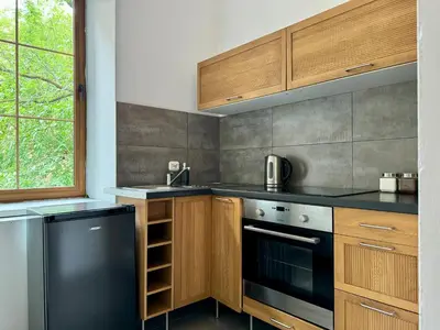 a kitchen with wooden cabinets and a black dishwasher at Millenium Apartments in Kraków