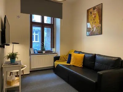 a living room with a black leather couch and yellow pillows at Millenium Apartments in Kraków