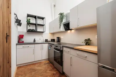 a kitchen with white cabinets and black appliances at Stylowy apartament - 6 sypialni - Kraków, Stare Miasto - by Upstairs in Kraków