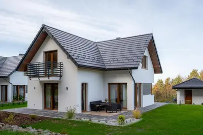 a white house with a black roof at Domki Kamieniec in Marcyporęba