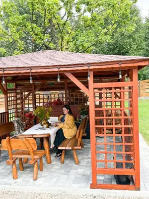 a woman sitting at a table in a gazebo at Domki Kamieniec in Marcyporęba
