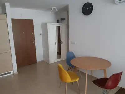 a room with a table and chairs and a clock at Apollo Apartments Zabłocie 21 in Kraków