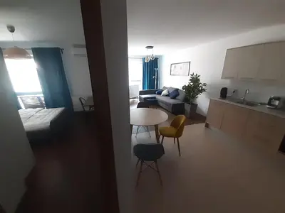 a living room and kitchen with a table and chairs at Apollo Apartments Zabłocie 21 in Kraków