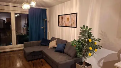 a living room with a couch and a plant at Apollo Apartments Zabłocie 21 in Kraków