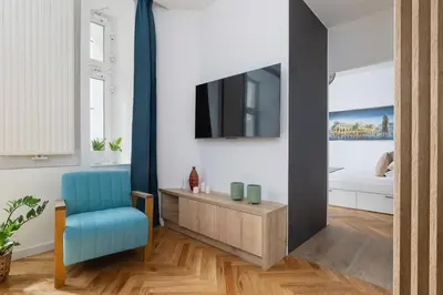 a living room with a tv and a blue chair at Apartment with Private Sauna - Dietla 21 street in Kraków