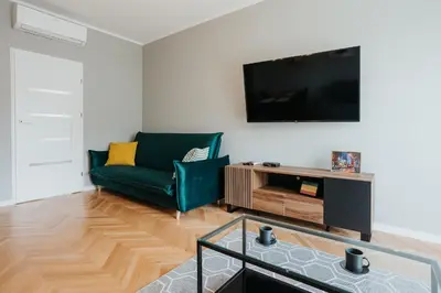 a living room with a green couch and a tv at Connecta Apartament in City Center with AC in Kraków