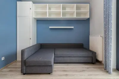a bed in a room with a blue wall at Bronowice Standard Studio by BookingHost in Kraków