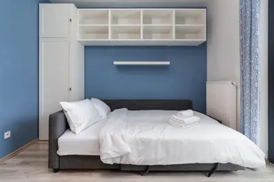 a bedroom with a bed with a blue wall at Bronowice Standard Studio by BookingHost in Kraków