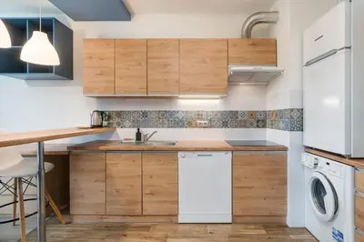 a kitchen with wooden cabinets and a washer and dryer at Bronowice Standard Studio by BookingHost in Kraków