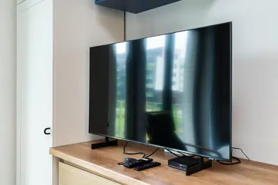 a large flat screen tv sitting on top of a dresser at Bronowice Standard Studio by BookingHost in Kraków