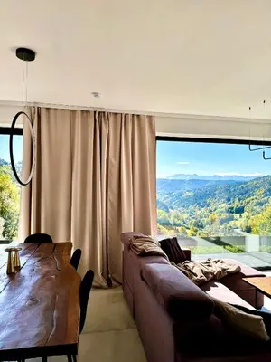 a living room with a couch and a large window at Bacówki Resort in Ochotnica Górna