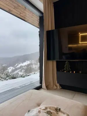 a bedroom with a large window and a tv at Bacówki Resort in Ochotnica Górna