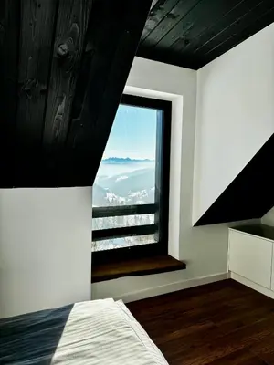 a bedroom with a bed and a large window at Bacówki Resort in Ochotnica Górna