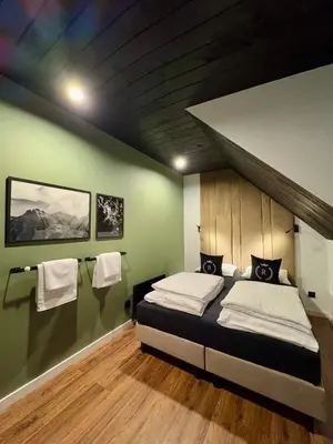 a bedroom with a bed and a green wall at Bacówki Resort in Ochotnica Górna