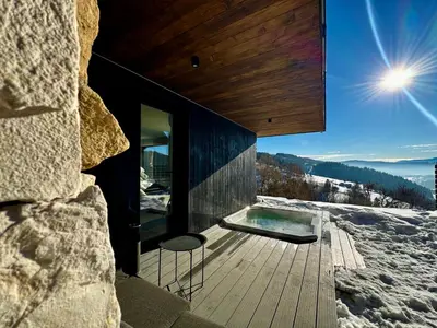 a house with a hot tub on a deck in the snow at Bacówki Resort in Ochotnica Górna