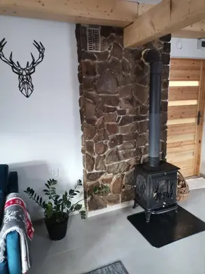 a wood stove in a room with a stone wall at Dom na Smyrakach in Zawoja