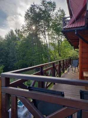 a wooden deck on a cabin with trees in the background at Dom na Smyrakach in Zawoja