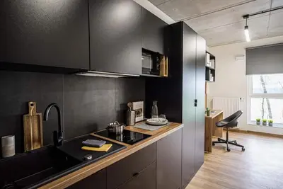 a kitchen with black cabinets and a counter top at SHED Living Kraków in Kraków