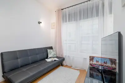 a living room with a black couch and a large window at Cosy Ariańska Apartment for 2 in Cracow Center by Noclegi Renters in Kraków