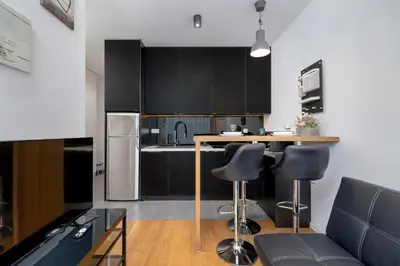 a kitchen with black cabinets and a counter with bar stools at Cosy Ariańska Apartment for 2 in Cracow Center by Noclegi Renters in Kraków