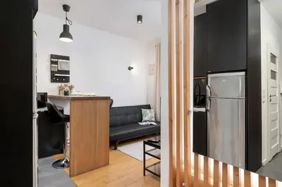 a kitchen and living room with a black couch at Cosy Ariańska Apartment for 2 in Cracow Center by Noclegi Renters in Kraków