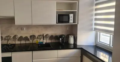 a kitchen with white cabinets and a black counter top at OMORIKA na Zamkowej in Kraków