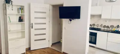 a white kitchen with white cabinets and a door at OMORIKA na Zamkowej in Kraków