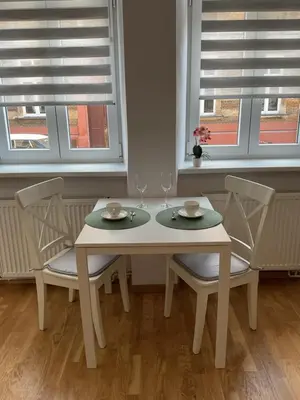 a white table with two chairs and two windows at OMORIKA na Zamkowej in Kraków