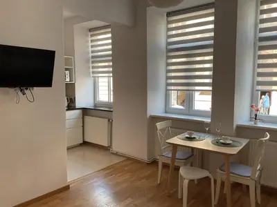 a living room with a table and chairs and windows at OMORIKA na Zamkowej in Kraków