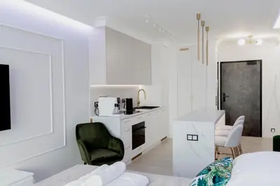 a white living room with a black and white kitchen at APARTAMENT WRAŻEŃ Kraków in Kraków