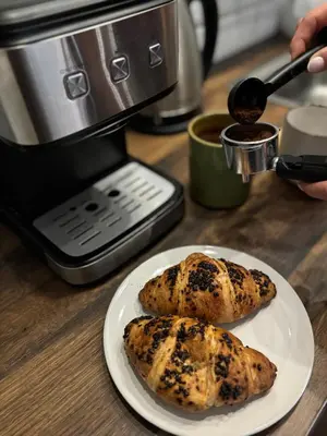 two muffins on a plate on a table with a coffee maker at Na Kamieńcu domki in Rzyki