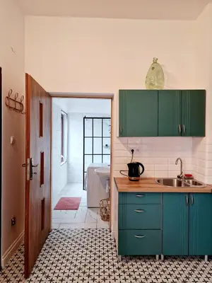 a kitchen with green cabinets and a sink and a bathroom at Apartament Kety Rynek Mickiewicza in Kęty
