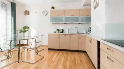 a kitchen with wooden cabinets and a glass table at Angel City, Sun & Snow in Kraków