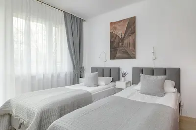 two beds in a white room with a window at Comfortable Apartment with Balcony in Krakow by Rent like home in Kraków