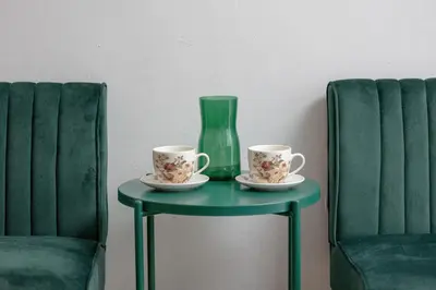 two cups and a vase on a table between two chairs at Comfortable Apartment with Balcony in Krakow by Rent like home in Kraków