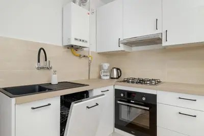 a kitchen with white cabinets and a sink at Comfortable Apartment with Balcony in Krakow by Rent like home in Kraków